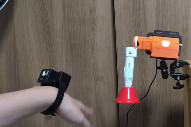 手首にM3キューブを付け、手の動きに連動してアームワンダがベルを鳴らす様子