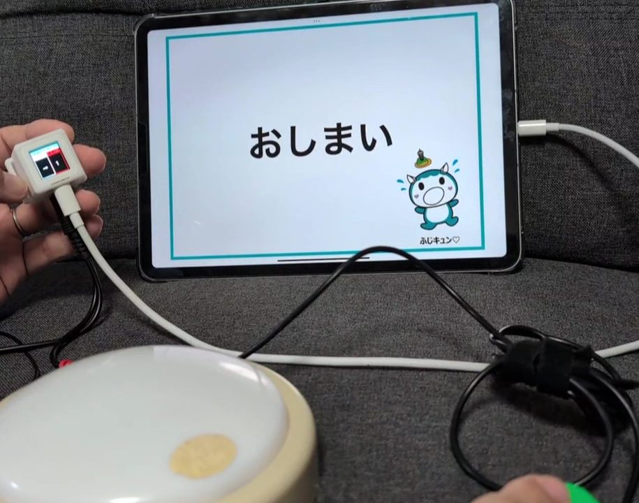 福祉スイッチとM3キューブでiPadのアプリを操作し、画面に「おしまい」と表示されている様子