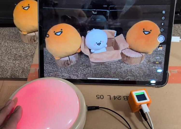 iPadのカメラアプリのシャッターボタンにカーソルを合わせ、光る大きな福祉スイッチを押して撮影している様子