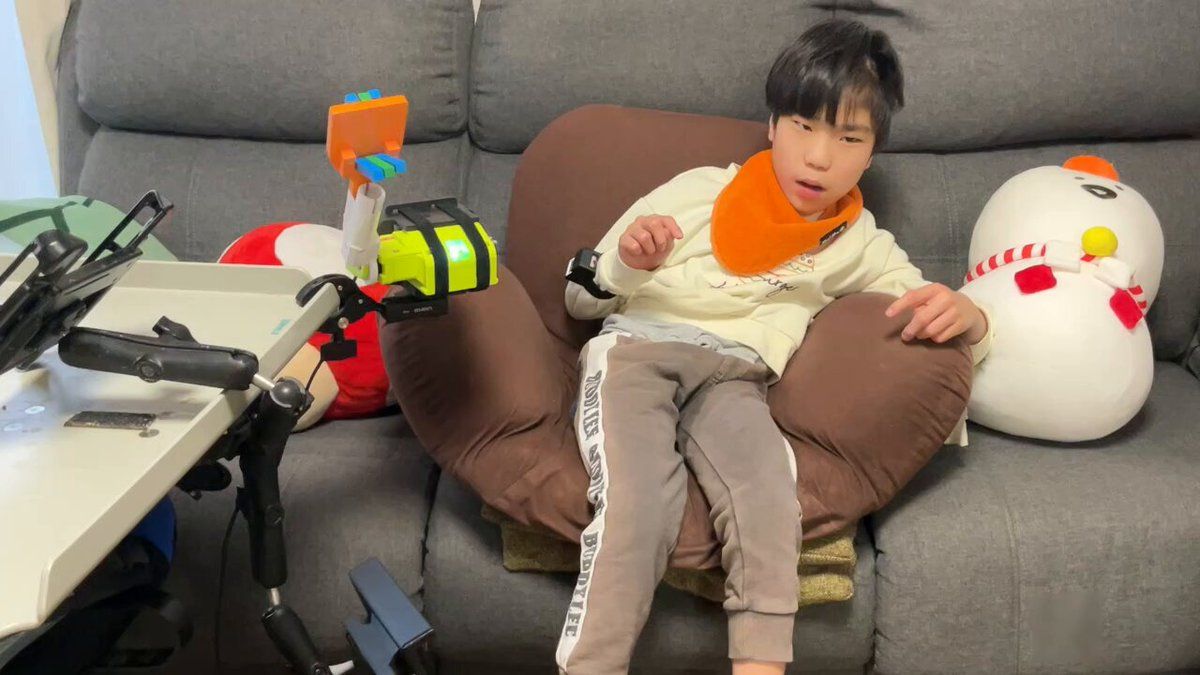 ソファに座った息子が手首にM3キューブを付け、腕の動きに連動してアームワンダが動く様子